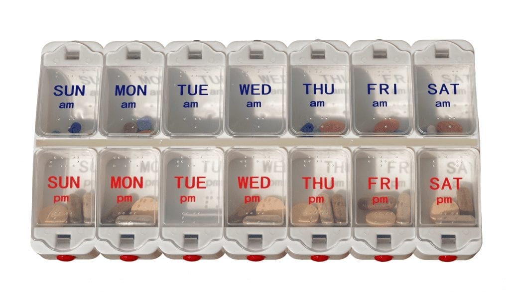 Elderly Medication Management Strategies A plastic pill planner box, with two rows of small containers labeled for each day of the week, the top row for AM and the bottom for PM